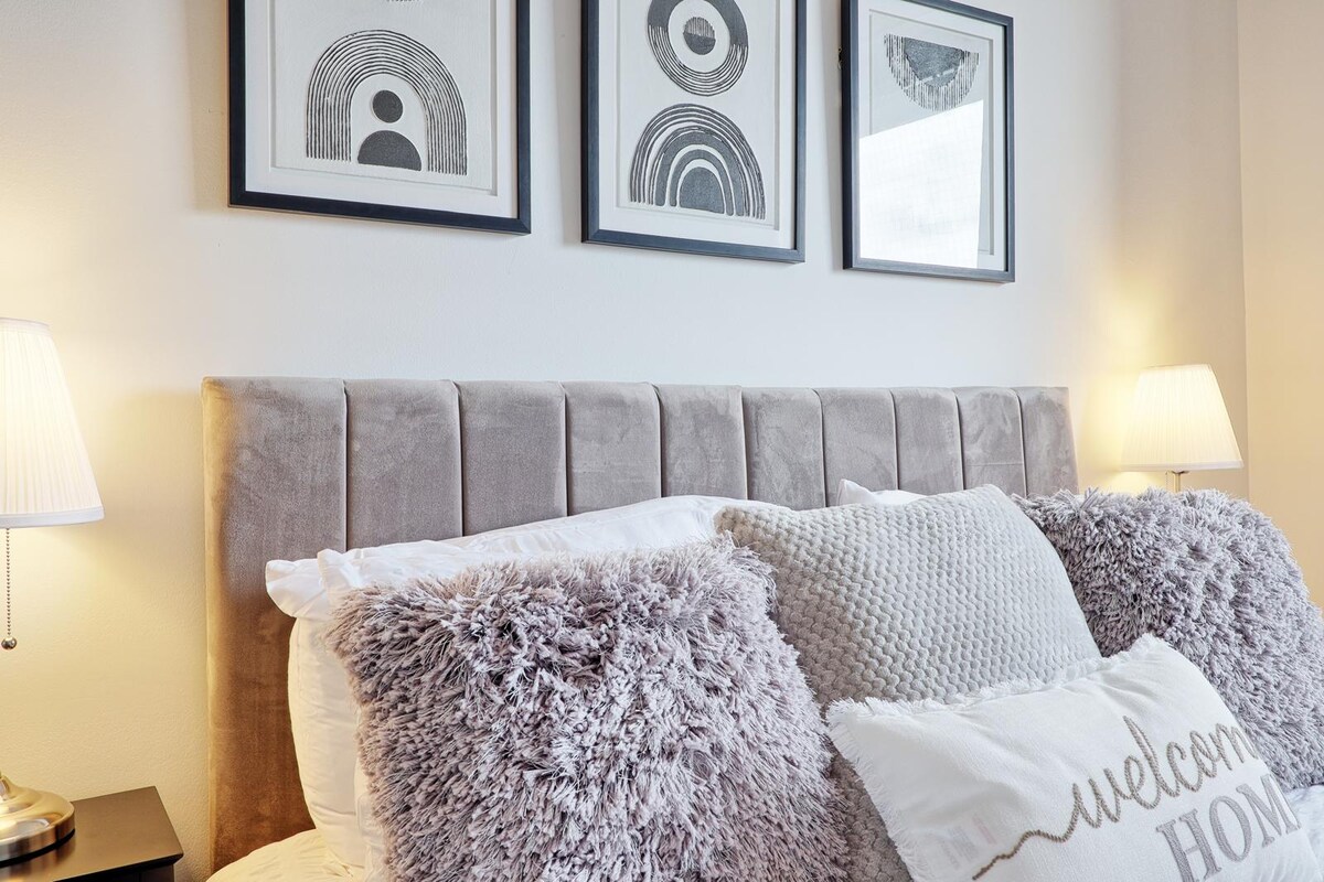 Styled bedroom detail with framed prints and upholstered headboard