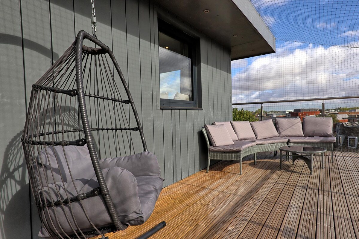 Outdoor lounge area with hanging chair and sofa on the penthouse terrace